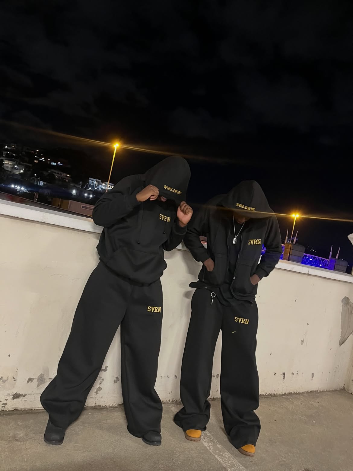 SVRN Worldwide black tracksuit set worn on rooftop at night